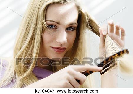 Stock Photo - Portrait of a young woman combing her hair. Fotosearch