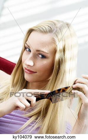 Stock Photo - Portrait of a young woman combing her hair. Fotosearch
