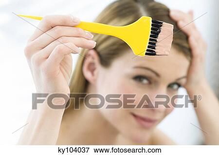 Portrait of a young woman dyeing her hair, little brush in her hand View Large Photo Image Stock Photo - Portrait of a young woman dyeing her hair, little brush in her hand. Fotosearch