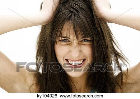 Stock Photo - Portrait of a young woman, hands on her brown hair (studio). Fotosearch
