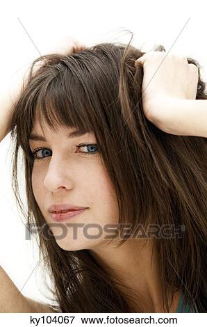 Stock Photo - Portrait of a young woman, hands on her hair, close up (studio). Fotosearch