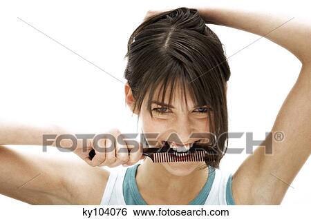 Stock Photograph - Portrait of a young woman holding a comb in her mouth. Fotosearch