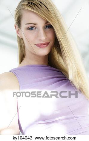 Stock Image - Portrait of a young woman looking at the camera, blond hair (studio). Fotosearch