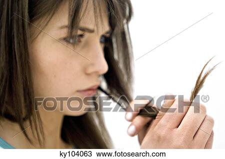 Portrait of a young woman looking at her hair, close up (studio) View Large Photo Image Stock Image - Portrait of a young woman looking at her hair, close up (studio). Fotosearch