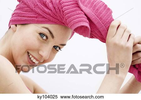 Stock Photography - Portrait of a young woman looking at the camera, pink hand towel on her head. Fotosearch