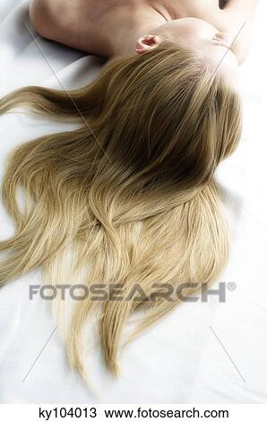 Stock Image - Portrait of a young woman lying, long hair on floor. Fotosearch