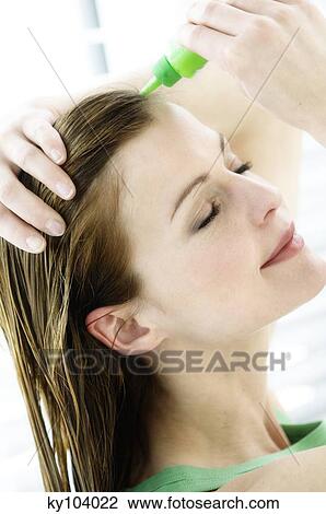 Portrait of a young woman pouring on hair lotion on her head View Large Photo Image Stock Image - Portrait of a young woman pouring on hair lotion on her head. Fotosearch