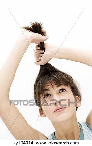 Portrait of a young woman pulling her hair, close up (studio) View Large Photo Image Picture - Portrait of a young woman pulling her hair, close up (studio). Fotosearch