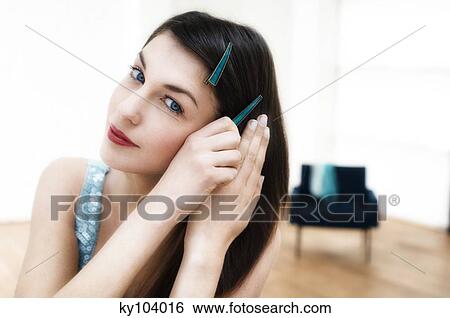 Stock Photograph - Portrait of a young woman putting a slide in her hair. Fotosearch