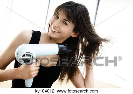 Portrait of a young woman using a hair drier View Large Photo Image Stock Image - Portrait of a young woman using a hair drier. Fotosearch