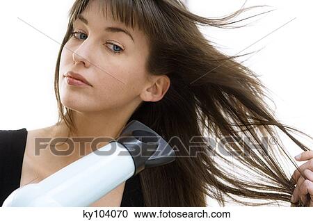 Portrait of a young woman using a hair drier View Large Photo Image Stock Image - Portrait of a young woman using a hair drier. Fotosearch