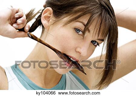 Stock Photograph - Portrait of a young woman with comb in her mouth. Fotosearch