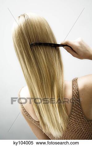 Stock Photography - Young woman combing her hair, view from the back. Fotosearch