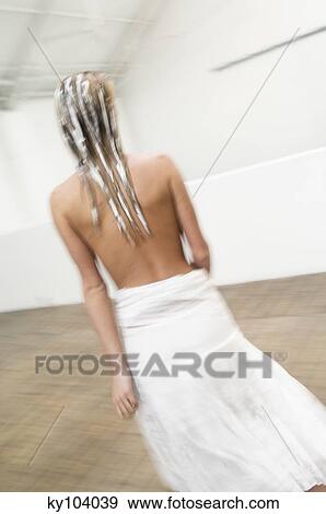 Stock Photo - Young woman with hair mask, view from the back, white skirt, blurred motion. Fotosearch