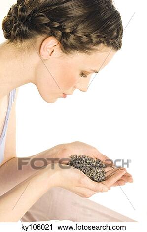 Stock Image - Portrait of a young woman holding grains of lavander. Fotosearch