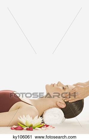 Stock Image - Woman having head massaged, water lily. Fotosearch