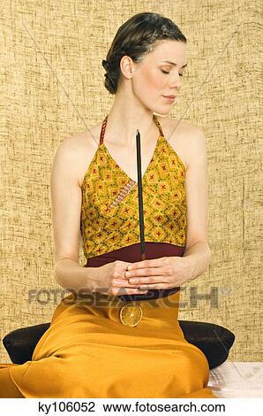 Stock Image - Woman holding incense stick. Fotosearch
