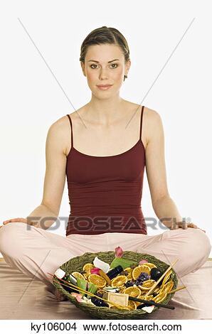 Woman sitting cross-legged, relaxation accessories in dish in front of her View Large Photo Image Picture - Woman sitting cross-legged, relaxation accessories in dish in front of her. Fotosearch