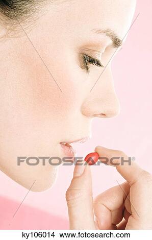 Picture - Woman taking tablet, close up (studio). Fotosearch