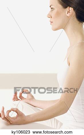 Stock Image - Young woman sitting in profile, yoga attitude. Fotosearch
