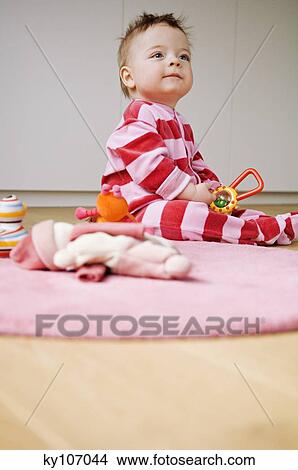 Baby playing, sitting on the floor View Large Photo Image Picture - Baby playing, sitting on the floor. Fotosearch