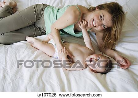 Mother and baby lying on the bed, view from above View Large Photo Image Stock Photograph - Mother and baby lying on the bed, view from above. Fotosearch