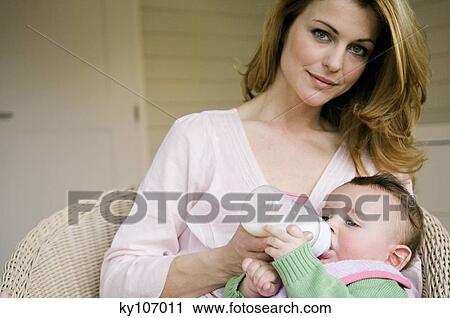 Mother bottle-feeding her baby View Large Photo Image Stock Image - Mother bottle-feeding her baby. Fotosearch