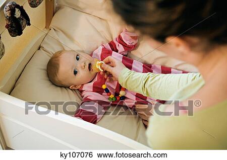Mother giving comforter to her baby in bed View Large Photo Image Stock Photograph - Mother giving comforter to her baby in bed. Fotosearch
