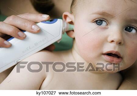 Mother taking her baby's temperature with an ear-thermometer View Large Photo Image Stock Photo - Mother taking her baby's temperature with an ear-thermometer. Fotosearch
