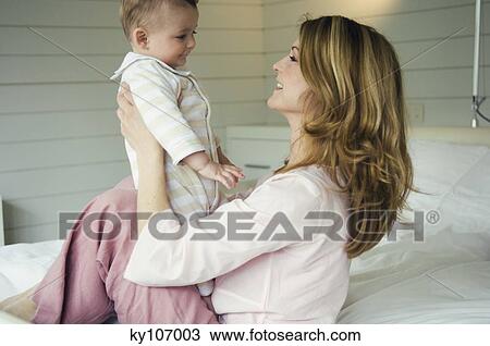 Woman and baby sitting on the bed, in profile View Large Photo Image Stock Image - Woman and baby sitting on the bed, in profile. Fotosearch