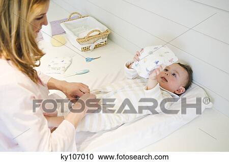 Woman undressing her baby lying View Large Photo Image Stock Image - Woman undressing her baby lying. Fotosearch