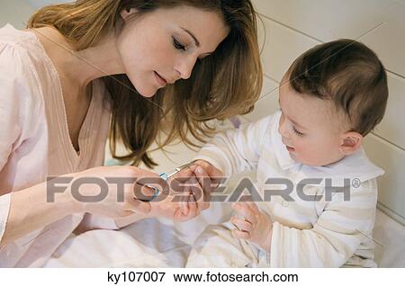 Young woman trimming her baby's fingernails View Large Photo Image Stock Photo - Young woman trimming her baby's fingernails. Fotosearch