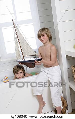 2 boys in bathroom, one having a bath, the other holding a model boat View Large Photo Image Stock Image - 2 boys in bathroom, one having a bath, the other holding a model boat. Fotosearch