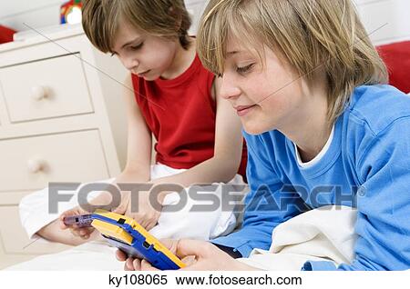 2 boys playing video games at home View Large Photo Image Stock Photography - 2 boys playing video games at home. Fotosearch