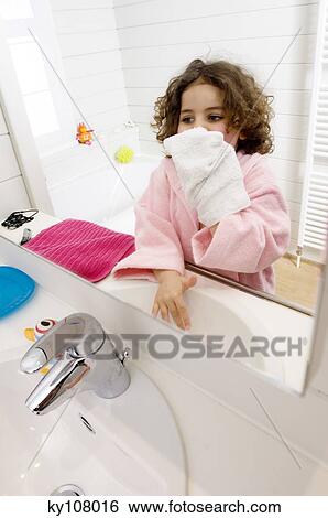 Stock Photograph - Little girl in bathroom with washcloth. Fotosearch
