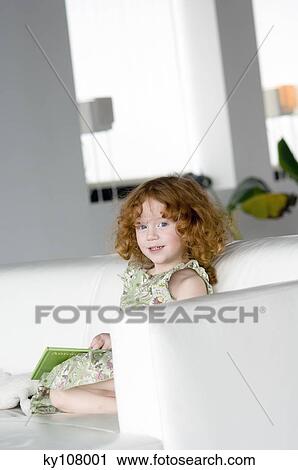 Stock Image - Little girl sitting on a sofa. Fotosearch
