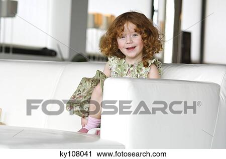 Little girl sitting on a sofa View Large Photo Image Stock Image - Little girl sitting on a sofa. Fotosearch
