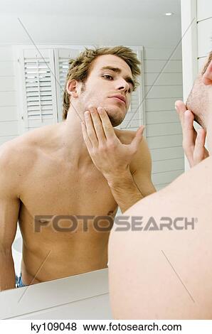 Stock Photo - Barechested man in front of bathroom mirror. Fotosearch
