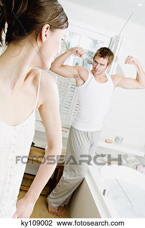 Couple in bathroom, woman watching man flexing muscles View Large Photo Image Stock Image - Couple in bathroom, woman watching man flexing muscles. Fotosearch