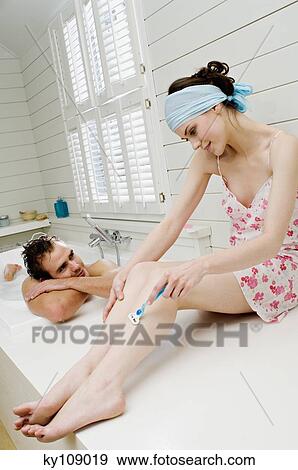 Stock Photo - Man having a bath and woman in nightgown shaving her legs. Fotosearch
