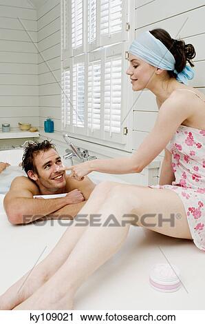Woman in nightgown sitting on tub edge spreading moisturizer on man's nose in bath View Large Photo Image Stock Image - Woman in nightgown sitting on tub edge spreading moisturizer on man's nose in bath. Fotosearch
