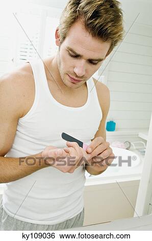 Young man filing his nails in front of bathroom mirror View Large Photo Image Stock Photograph - Young man filing his nails in front of bathroom mirror. Fotosearch