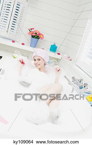 Picture - Young woman having a bath, smiling for the camera. Fotosearch
