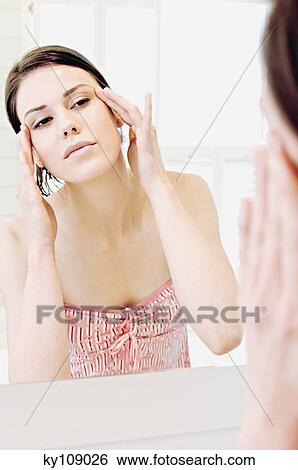 Stock Photograph - Young woman in front of bathroom mirror. Fotosearch