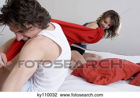 Couple having a pillow fight on a bed View Large Photo Image Stock Image - Couple having a pillow fight on a bed. Fotosearch