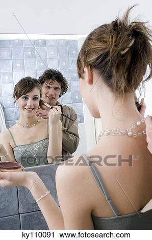 Man fastening necklace of a woman applying make-up in front of bathroom mirror View Large Photo Image Stock Image - Man fastening necklace of a woman applying make-up in front of bathroom mirror. Fotosearch