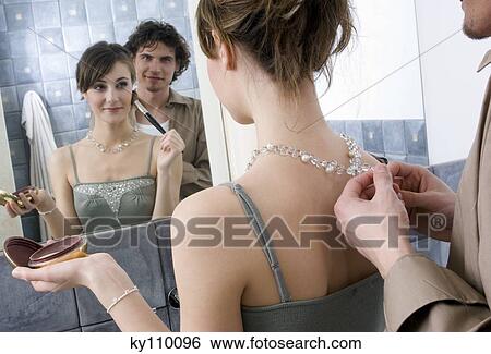 Man fastening necklace of a woman applying make-up in front of bathroom mirror View Large Photo Image Stock Photograph - Man fastening necklace of a woman applying make-up in front of bathroom mirror. Fotosearch