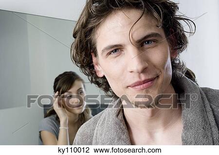 Man in bathrobe looking at the camera in bathroom, woman in background View Large Photo Image Stock Image - Man in bathrobe looking at the camera in bathroom, woman in background. Fotosearch