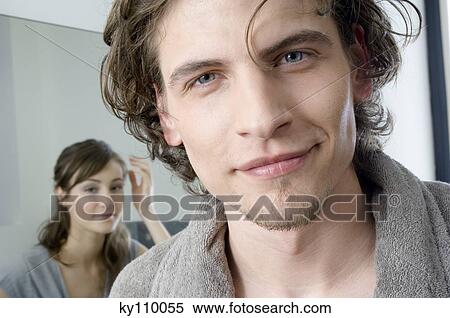 Man in bathrobe looking at the camera in bathroom, woman in background View Large Photo Image Stock Photography - Man in bathrobe looking at the camera in bathroom, woman in background. Fotosearch