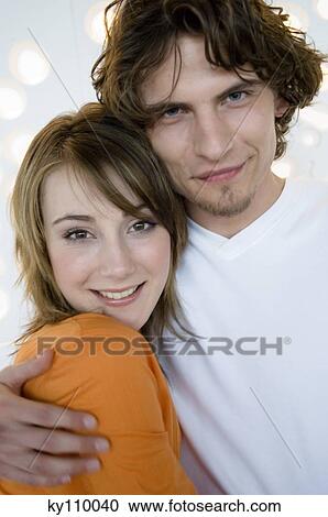 Stock Image - Portrait of a couple embracing, smiling for the camera. Fotosearch